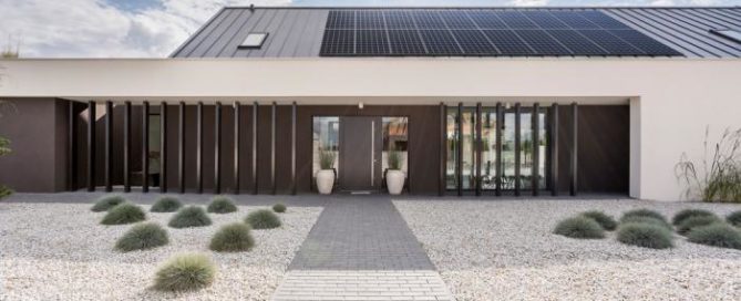 Modern home with rooftop solar panels and minimalist landscaping, demonstrating sustainable energy solutions.